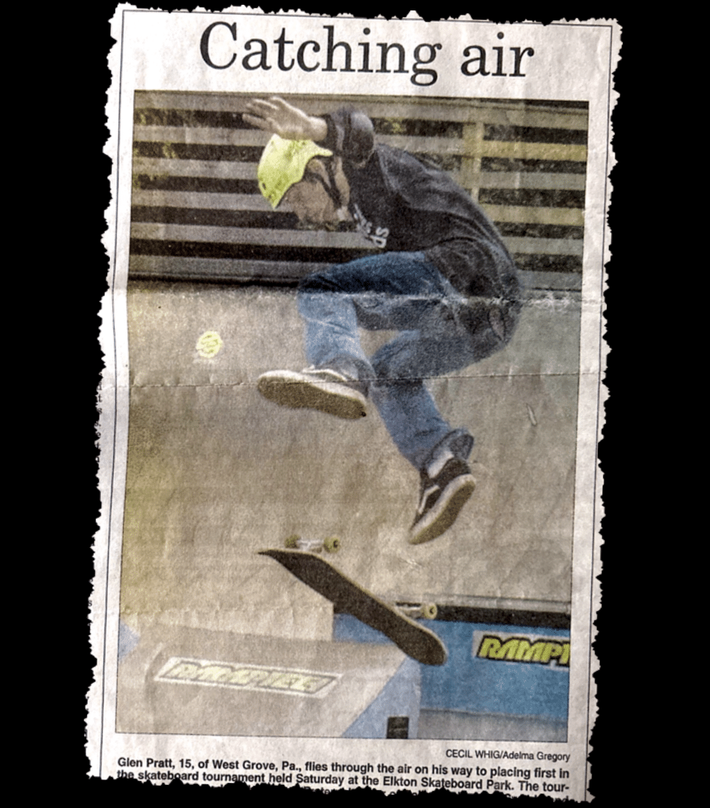 A scan of an old photograph of James Glen Pratt, founder of Marketing for Gold winning gold at a skateboarding contest flying through the air. 